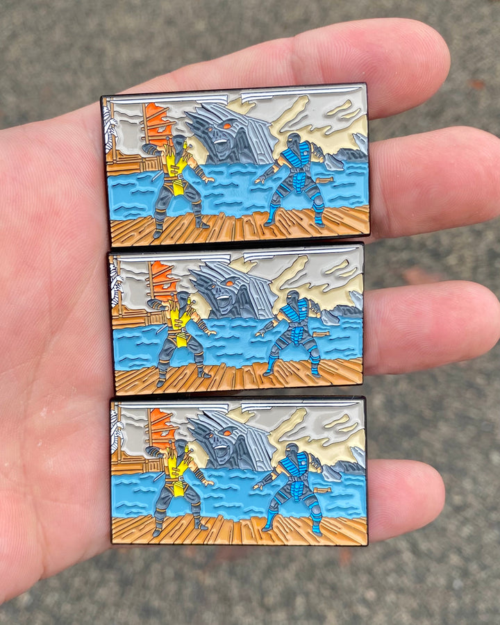 Three Mortal Kombat Fatality enamel pins held in hand